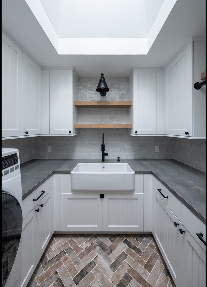 Photo of a large country u-shaped dedicated laundry room in San Francisco with a farmhouse sink, beaded inset cabinets, white cabinets, quartz benchtops, grey splashback, porcelain splashback, ceramic floors, a side-by-side washer and dryer, multi-coloured floor and grey benchtop.