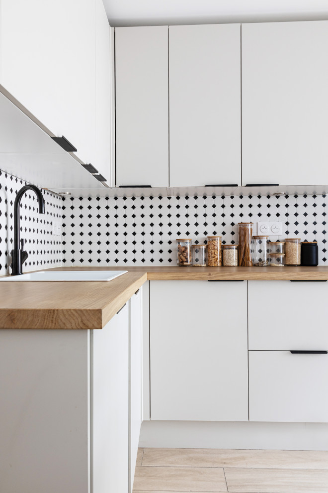 Modern inredning av ett mellanstort beige beige kök, med en undermonterad diskho, släta luckor, vita skåp, träbänkskiva, integrerade vitvaror, ljust trägolv och beiget golv