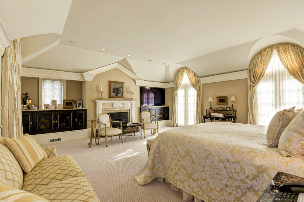 На фото: большая хозяйская спальня с бежевыми стенами, ковровым покрытием и коричневым полом без камина с