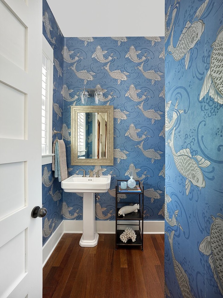 Beach style powder room in Other with blue walls, medium hardwood floors, a pedestal sink and brown floor.