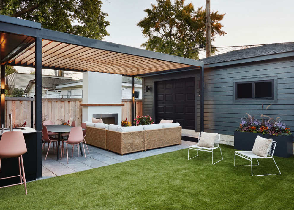 Ispirazione per un patio o portico minimalista dietro casa con un caminetto e una pergola