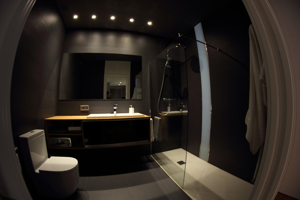 Ejemplo de cuarto de baño clásico renovado pequeño con armarios abiertos, puertas de armario de madera clara, ducha abierta, sanitario de una pieza, baldosas y/o azulejos negros, baldosas y/o azulejos de cerámica, paredes negras, suelo de baldosas de cerámica, aseo y ducha, lavabo integrado, encimera de madera y suelo negro