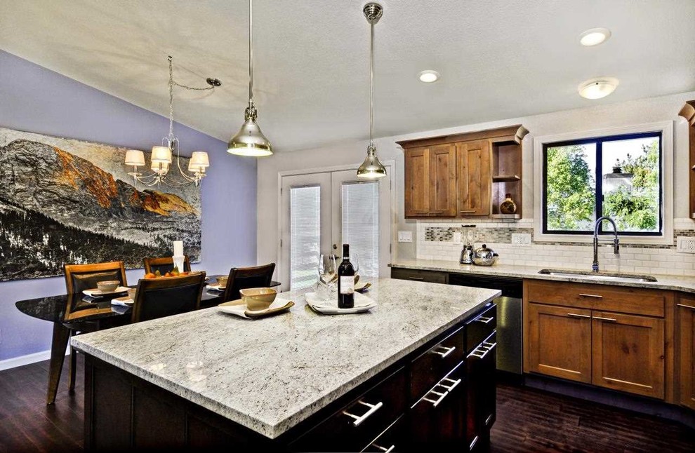 Mid-sized transitional l-shaped dark wood floor open concept kitchen photo in Boise with an undermount sink, shaker cabinets, medium tone wood cabinets, granite countertops, white backsplash, ceramic backsplash, stainless steel appliances and an island