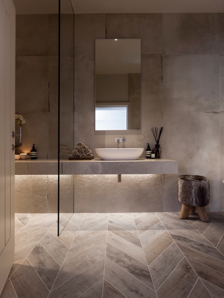 This is an example of a mid-sized contemporary master bathroom in Cheshire with furniture-like cabinets, tile benchtops, a freestanding tub, a shower/bathtub combo, a wall-mount toilet, white tile, porcelain tile, white walls, porcelain floors and a vessel sink.
