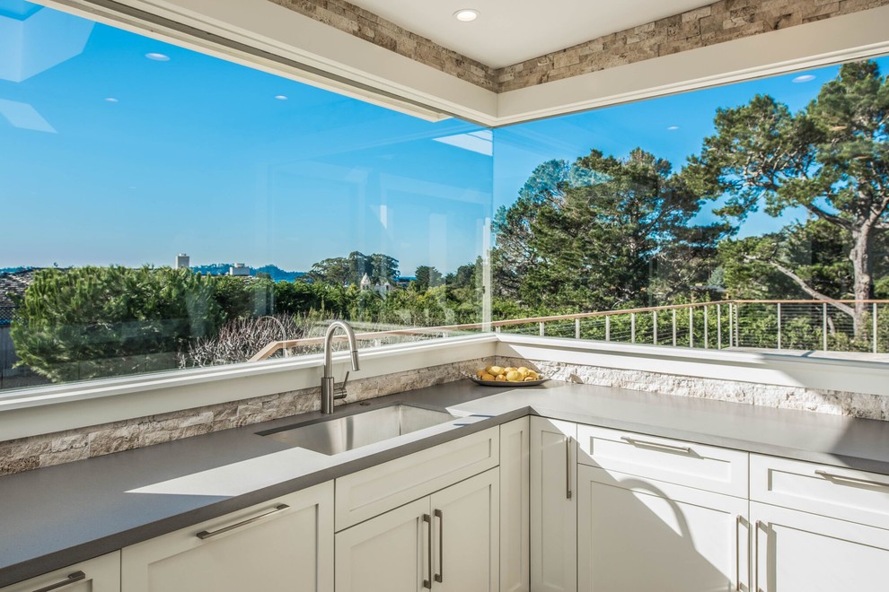 Example of a large transitional u-shaped light wood floor open concept kitchen design in Orange County with a single-bowl sink, shaker cabinets, white cabinets, stone tile backsplash, no island, beige backsplash and gray countertops