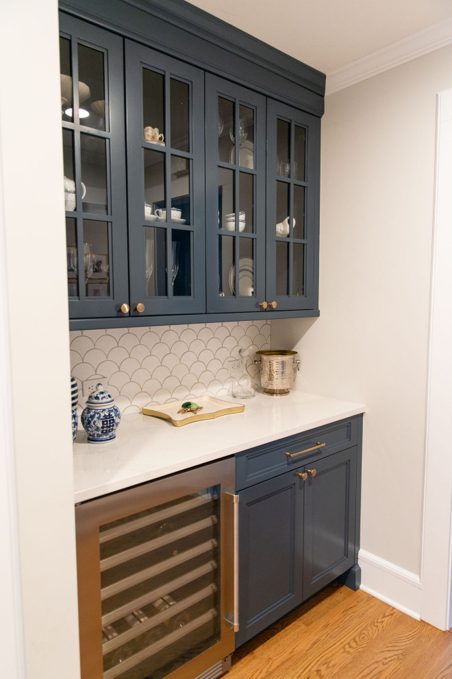 Small transitional galley light wood floor and brown floor dry bar photo in New York with glass-front cabinets, blue cabinets, quartz countertops, white backsplash, ceramic backsplash and white countertops