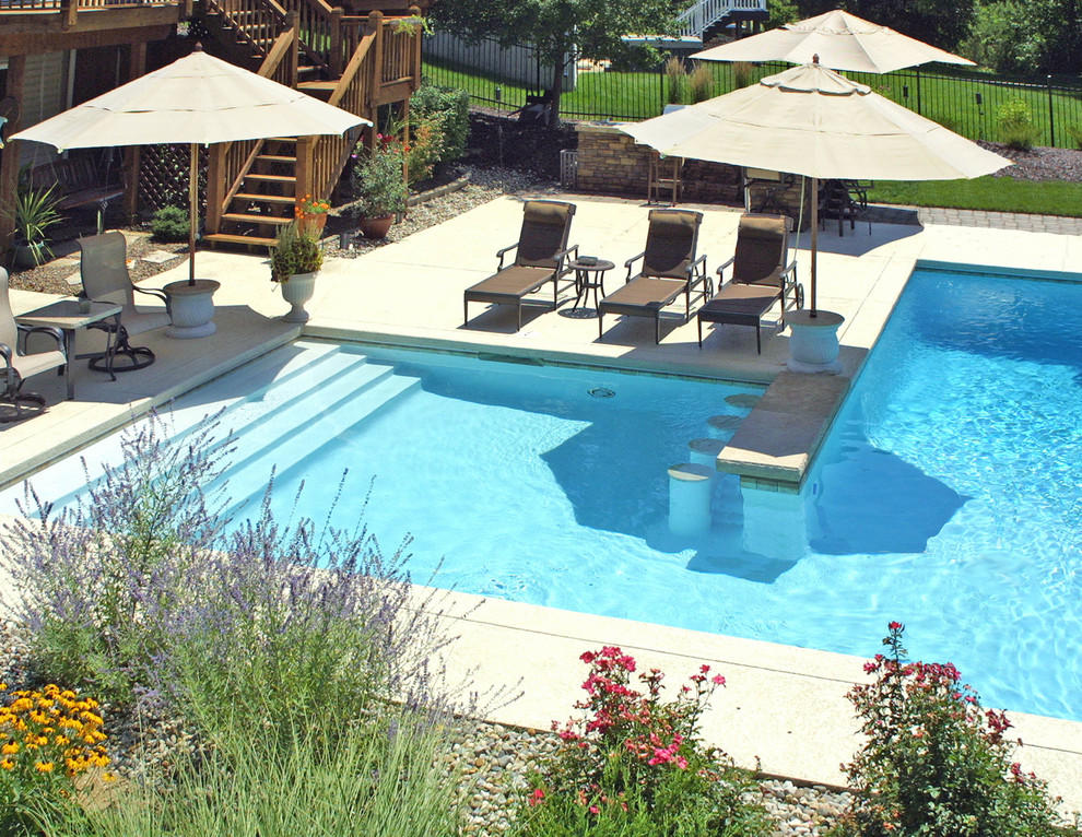 Inspiration for a large modern backyard l-shaped lap pool in St Louis with stamped concrete.