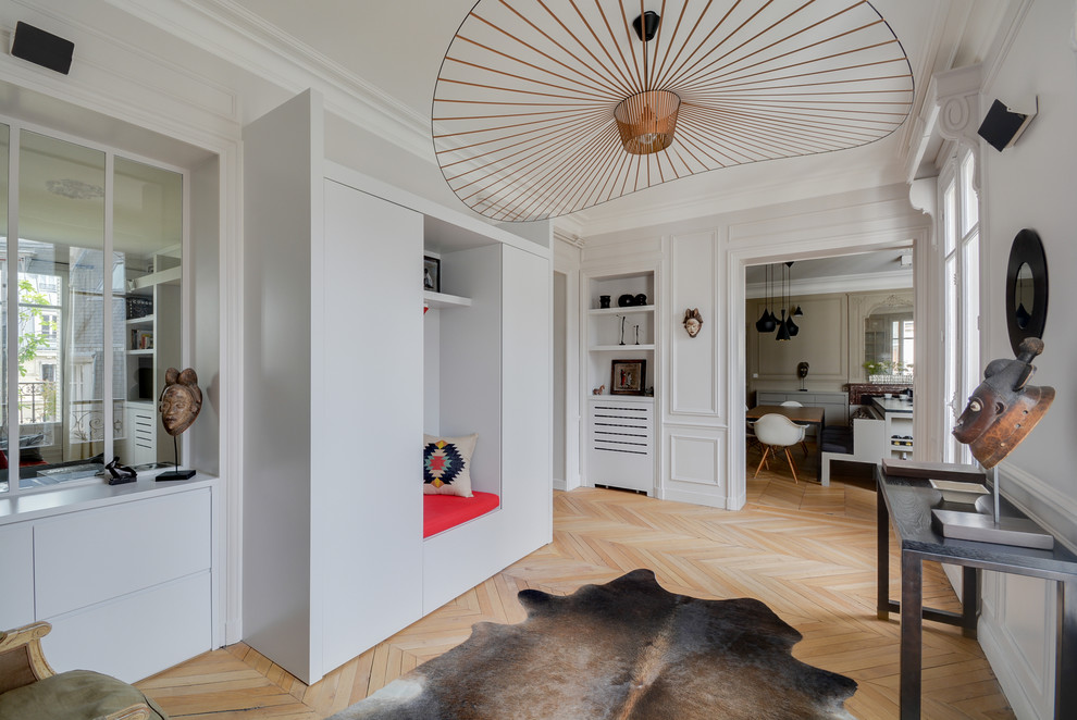 This is an example of a contemporary foyer in Paris with grey walls and light hardwood floors.