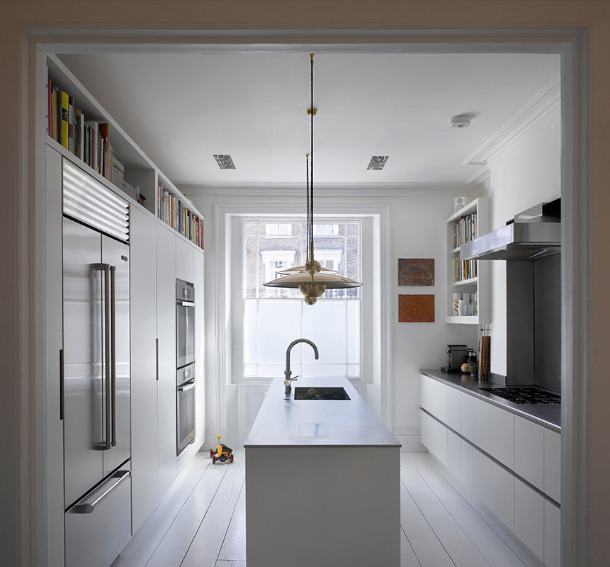 Medium sized contemporary galley kitchen/diner in London with flat-panel cabinets, white cabinets, stainless steel worktops, grey splashback, stainless steel appliances, painted wood flooring, an island, white floors and grey worktops.