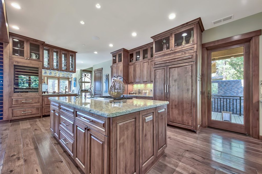 Example of a huge transitional u-shaped medium tone wood floor and multicolored floor open concept kitchen design with a double-bowl sink, raised-panel cabinets, medium tone wood cabinets, granite countertops, multicolored backsplash, stone slab backsplash, paneled appliances, an island and multicolored countertops