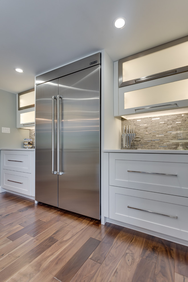 This is an example of a mid-sized contemporary galley eat-in kitchen in DC Metro with a double-bowl sink, shaker cabinets, white cabinets, quartzite benchtops, grey splashback, stone tile splashback, stainless steel appliances, medium hardwood floors and with island.