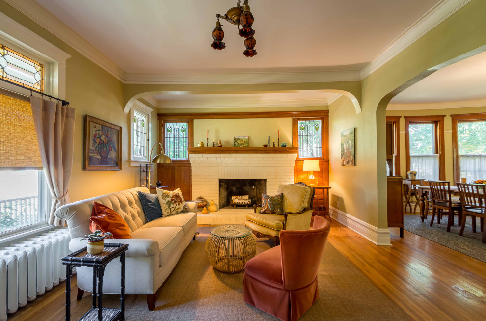 Photo of a mid-sized traditional enclosed living room in Chicago with beige walls, medium hardwood floors, a standard fireplace, a brick fireplace surround, no tv, brown floor, wallpaper and wallpaper.