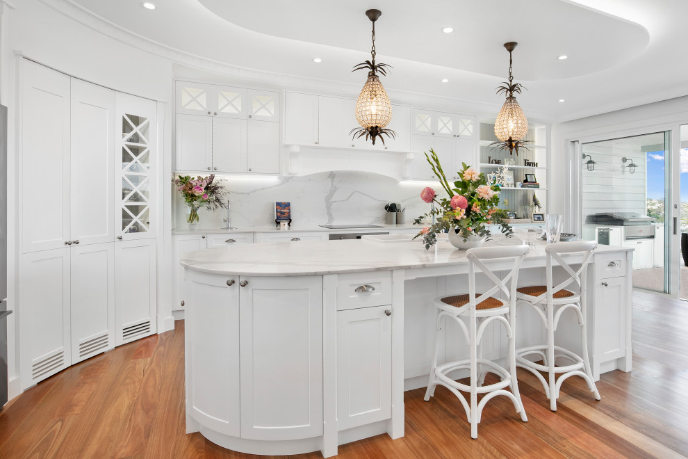 Inspiration for a large beach style kitchen pantry in Sydney with shaker cabinets, white cabinets, marble benchtops, medium hardwood floors, with island, grey benchtop, grey splashback, marble splashback and stainless steel appliances.