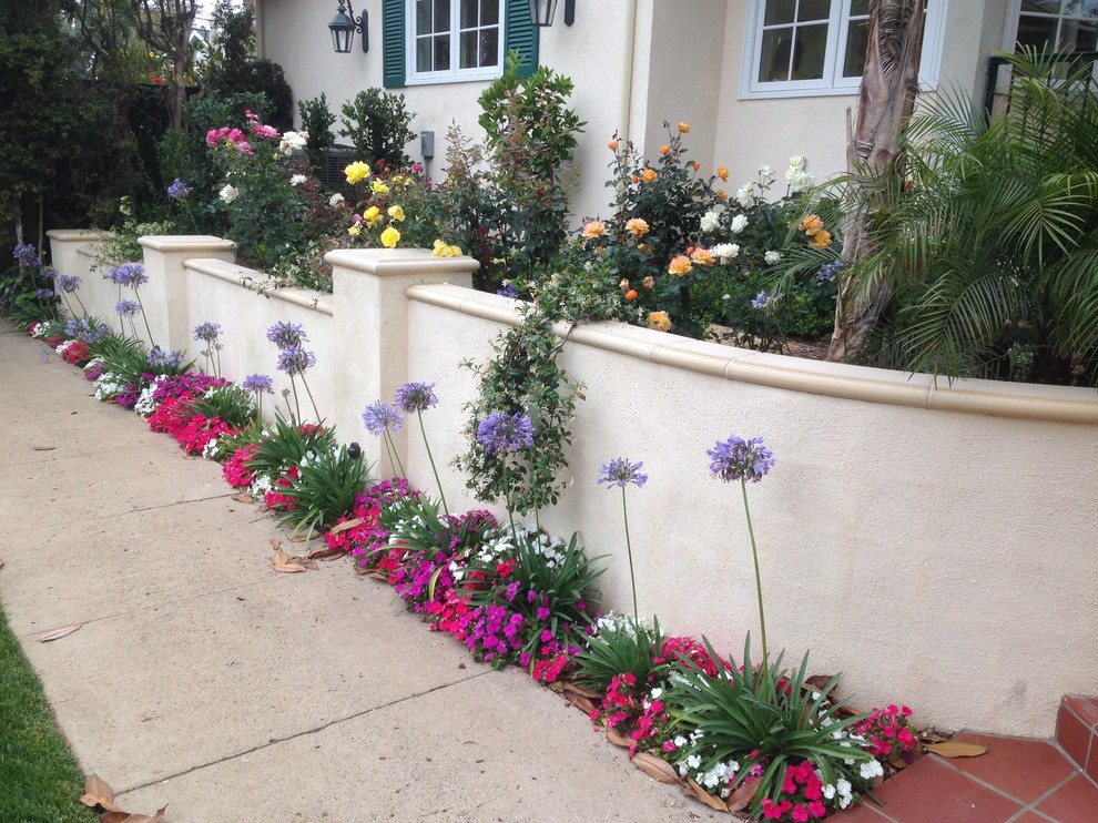 This is an example of a mid-sized beach style front yard formal garden in Los Angeles with a retaining wall and brick pavers.