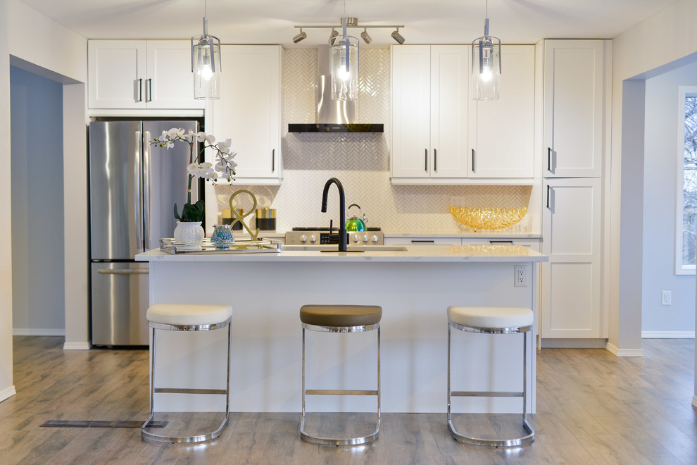 Inspiration for a transitional galley medium tone wood floor and brown floor kitchen remodel with an undermount sink, shaker cabinets, medium tone wood cabinets, stainless steel appliances, an island and white countertops