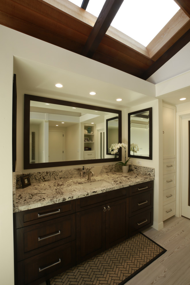 Expansive traditional master bathroom in Los Angeles with shaker cabinets, dark wood cabinets, an undermount tub, white walls, ceramic floors, an undermount sink, granite benchtops, grey floor, an open shower, beige benchtops, a single vanity, a built-in vanity and exposed beam.