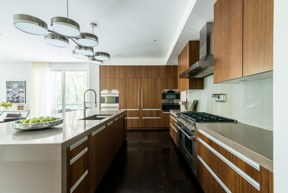 This is an example of a mid-sized midcentury l-shaped eat-in kitchen in Atlanta with an undermount sink, shaker cabinets, medium wood cabinets, concrete benchtops, grey splashback, granite splashback, stainless steel appliances, dark hardwood floors, with island, brown floor and grey benchtop.