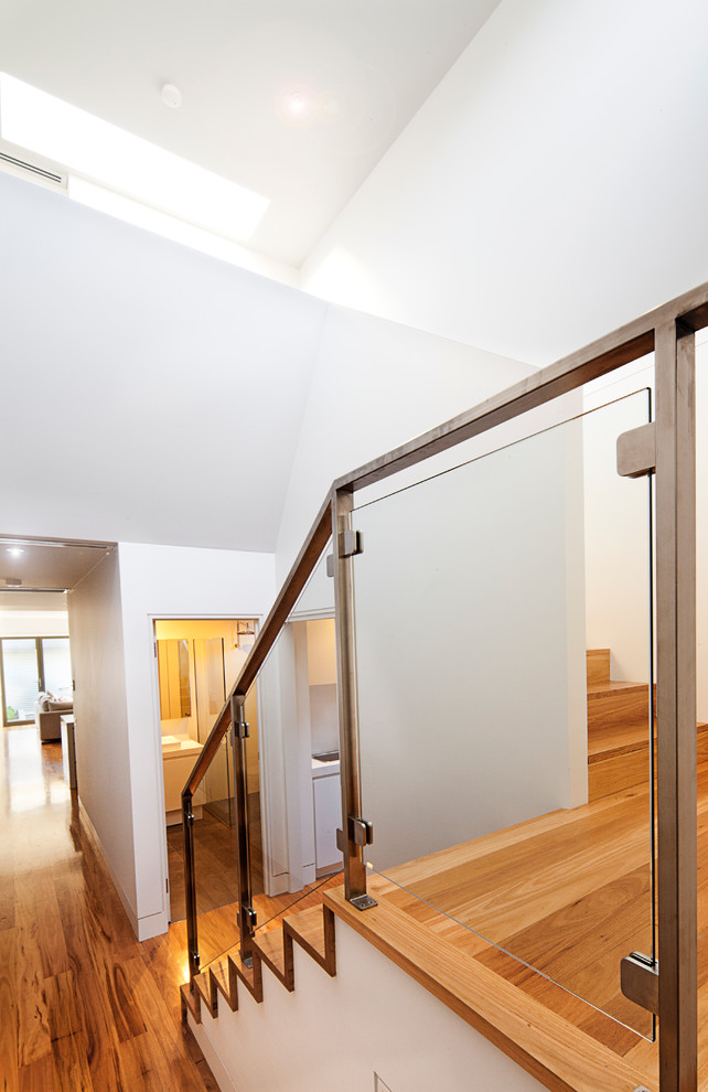 Photo of a small modern hallway in Melbourne with white walls and medium hardwood floors.