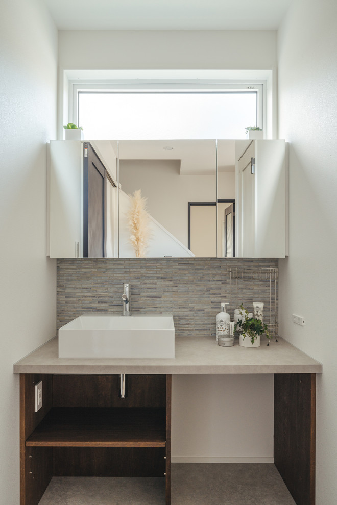 This is an example of a powder room in Other with white cabinets, white walls, light hardwood floors, a wall-mount sink, beige floor, beige benchtops, wallpaper and wallpaper.