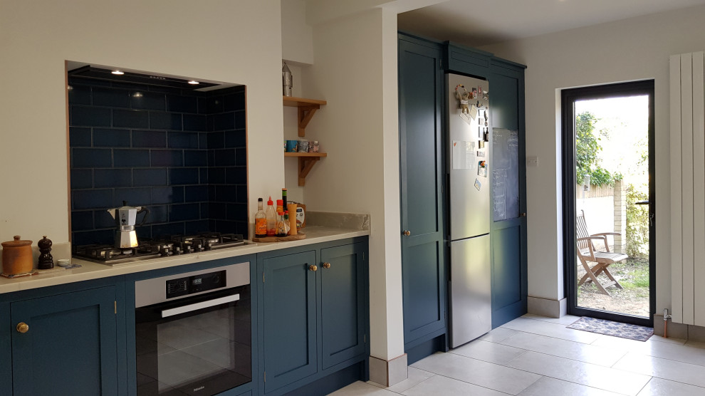 This is an example of a mid-sized transitional u-shaped eat-in kitchen in London with an undermount sink, shaker cabinets, blue cabinets, quartzite benchtops, blue splashback, subway tile splashback, stainless steel appliances, porcelain floors, grey floor and grey benchtop.