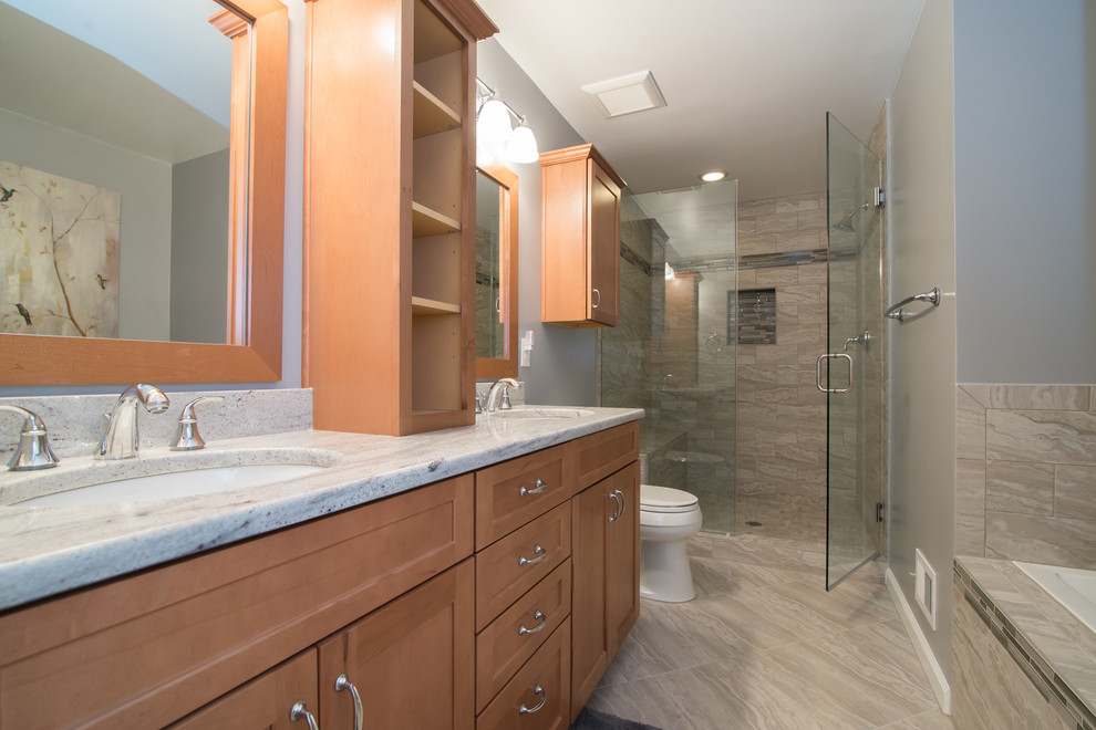 Mid-sized traditional master bathroom in DC Metro with an undermount sink, recessed-panel cabinets, medium wood cabinets, a drop-in tub, an alcove shower, a two-piece toilet, beige tile, porcelain tile, blue walls, porcelain floors, granite benchtops, grey floor and a hinged shower door.