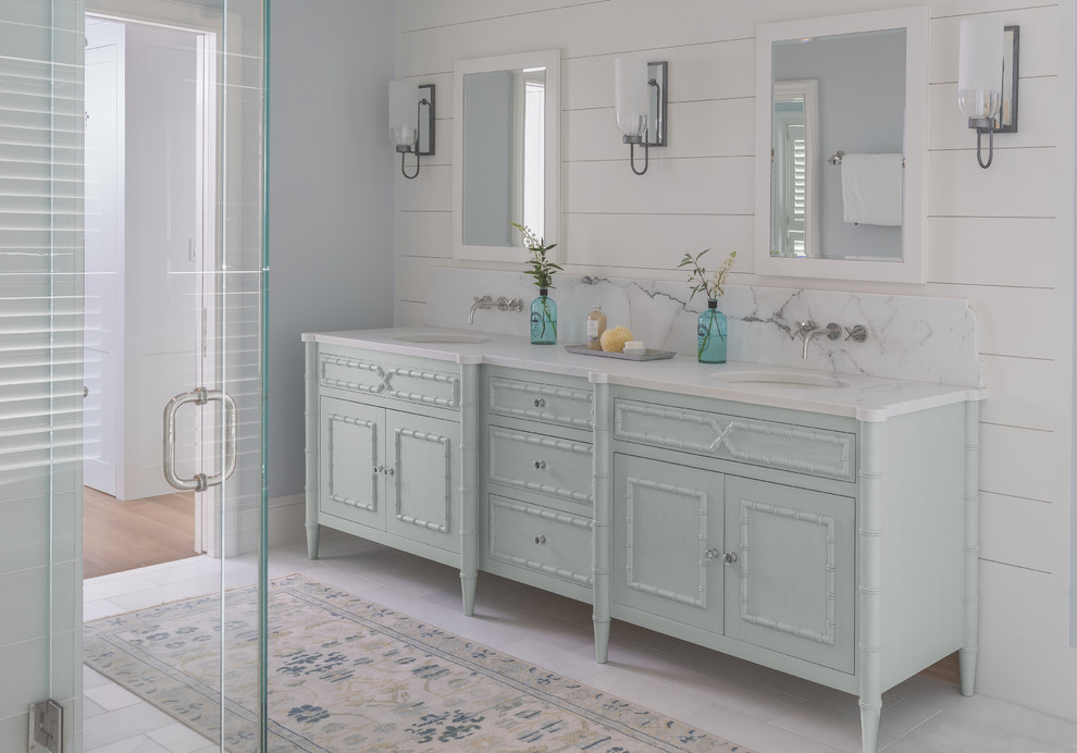 Photo of a mid-sized beach style master bathroom in Portland Maine with furniture-like cabinets, green cabinets, a corner shower, grey walls, porcelain floors, an undermount sink, marble benchtops, white floor and a hinged shower door.