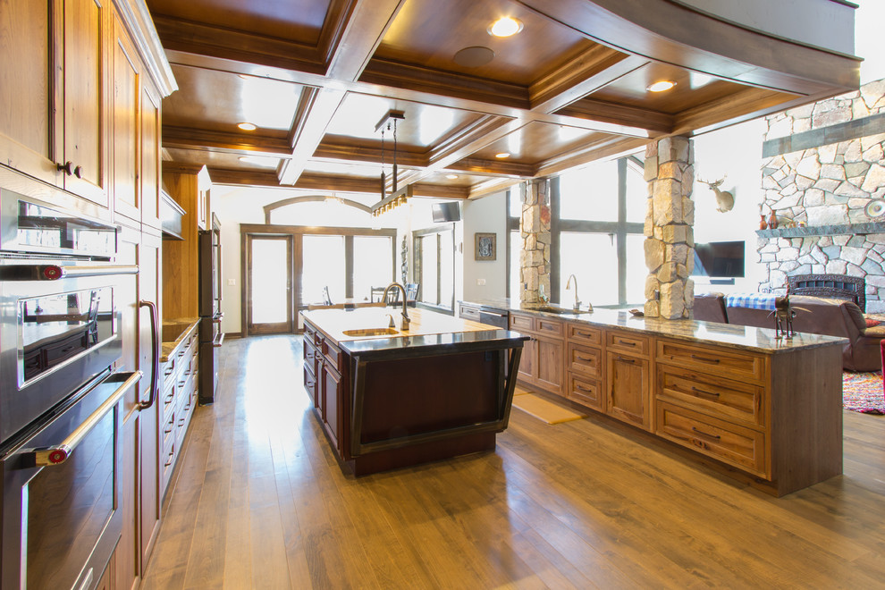 Mountain style brown floor open concept kitchen photo with an undermount sink, flat-panel cabinets, medium tone wood cabinets, quartz countertops, stainless steel appliances and two islands