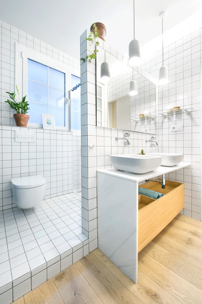 Mid-sized scandinavian 3/4 bathroom in Madrid with a corner shower, a wall-mount toilet, white tile, ceramic tile, white walls, ceramic floors, a vessel sink and solid surface benchtops.