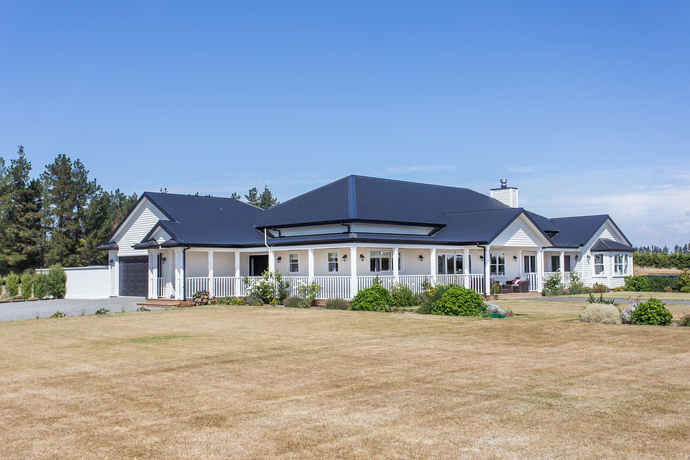This is an example of a Large country One-storey White house exterior in Christchurch With Mixed Siding, a Hip Roof and a Mixed Roof.