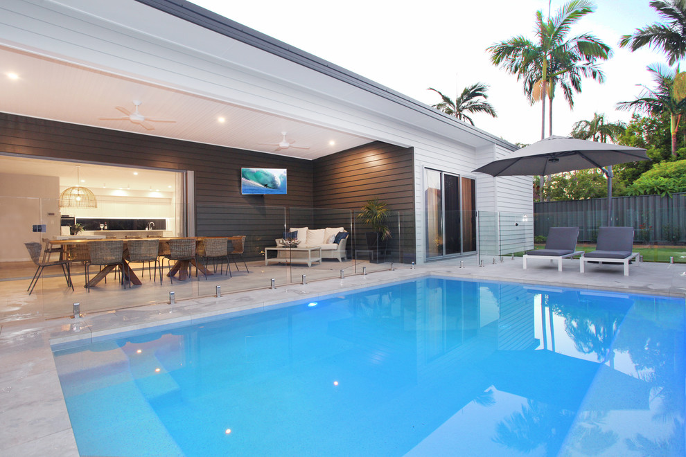 Design ideas for a mid-sized contemporary side yard rectangular pool in Sunshine Coast with a pool house and tile.