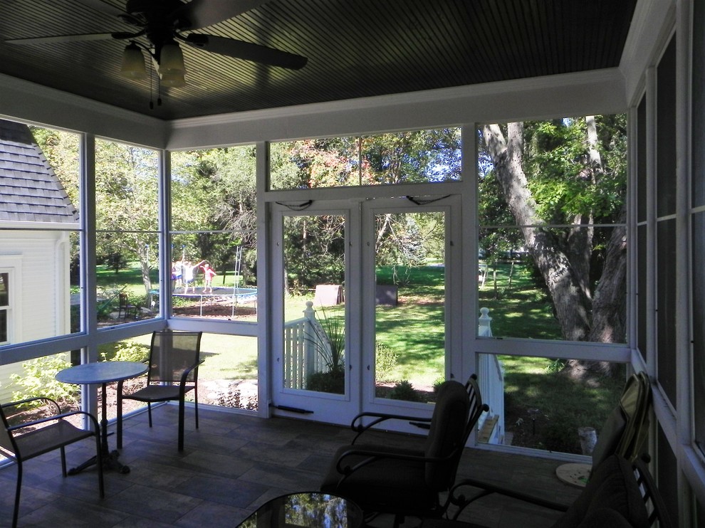Photo of a traditional backyard screened-in verandah in Chicago with brick pavers and a roof extension.