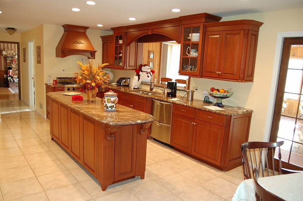 Small traditional galley eat-in kitchen in New York with an undermount sink, raised-panel cabinets, medium wood cabinets, granite benchtops, beige splashback, stainless steel appliances, ceramic floors and with island.