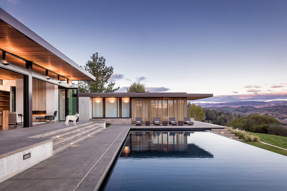 This is an example of a contemporary backyard rectangular infinity pool in San Francisco with concrete pavers.