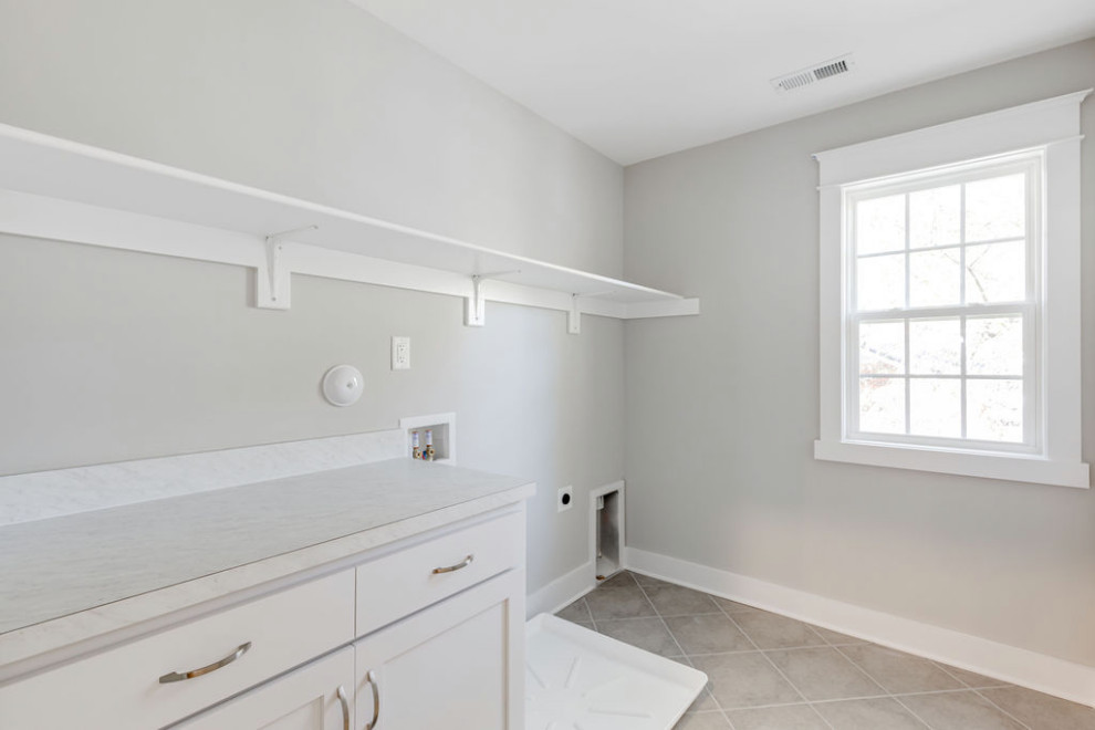 This is an example of a mid-sized traditional single-wall dedicated laundry room in Richmond with recessed-panel cabinets, white cabinets, laminate benchtops, grey walls, ceramic floors, a side-by-side washer and dryer, grey floor and white benchtop.