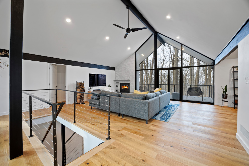 Idée de décoration pour un salon design de taille moyenne et ouvert avec un mur blanc, parquet clair, une cheminée standard, un manteau de cheminée en pierre, un téléviseur fixé au mur, un sol marron et poutres apparentes.
