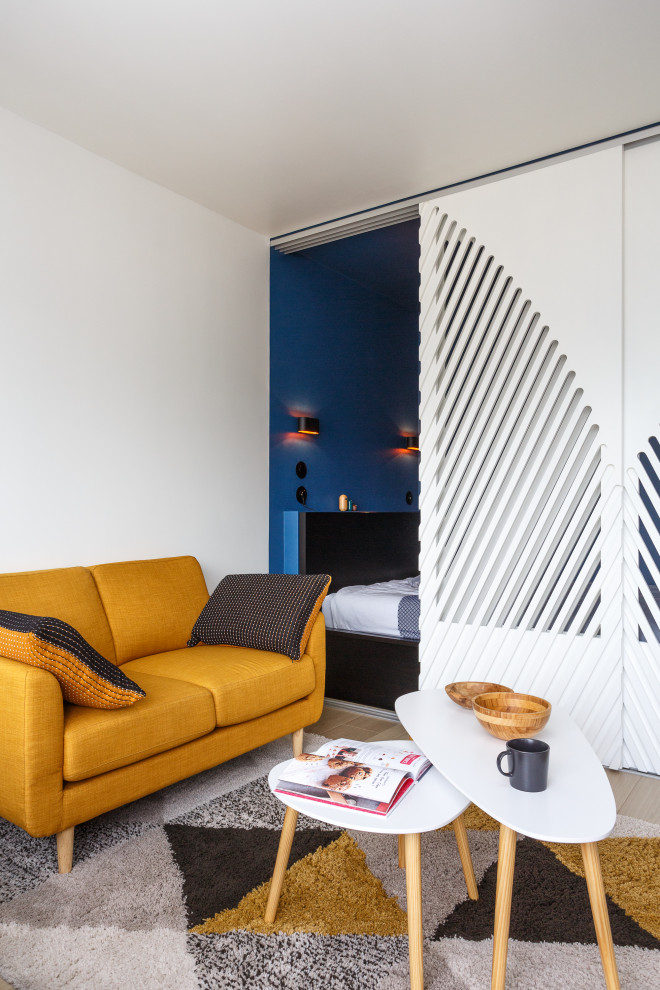 Aménagement d'une petite chambre scandinave avec un mur bleu, parquet clair et un sol marron.