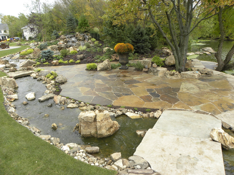 Inspiration for an expansive traditional backyard partial sun garden for summer in Chicago with a water feature and natural stone pavers.
