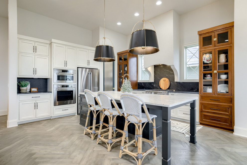 Inspiration for a timeless medium tone wood floor and gray floor open concept kitchen remodel in Omaha with a farmhouse sink, shaker cabinets, granite countertops, black backsplash, granite backsplash, stainless steel appliances and an island