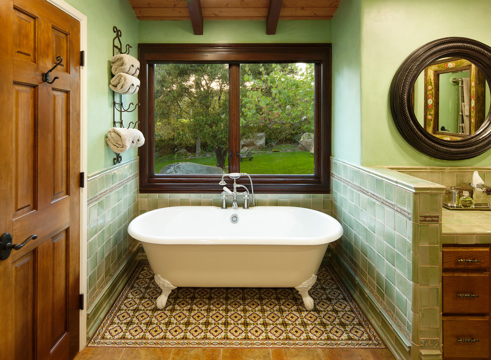 Inspiration for a large mediterranean master bathroom in Santa Barbara with raised-panel cabinets, medium wood cabinets, a claw-foot tub, green tile, ceramic tile, green walls, mosaic tile floors, tile benchtops and multi-coloured floor.