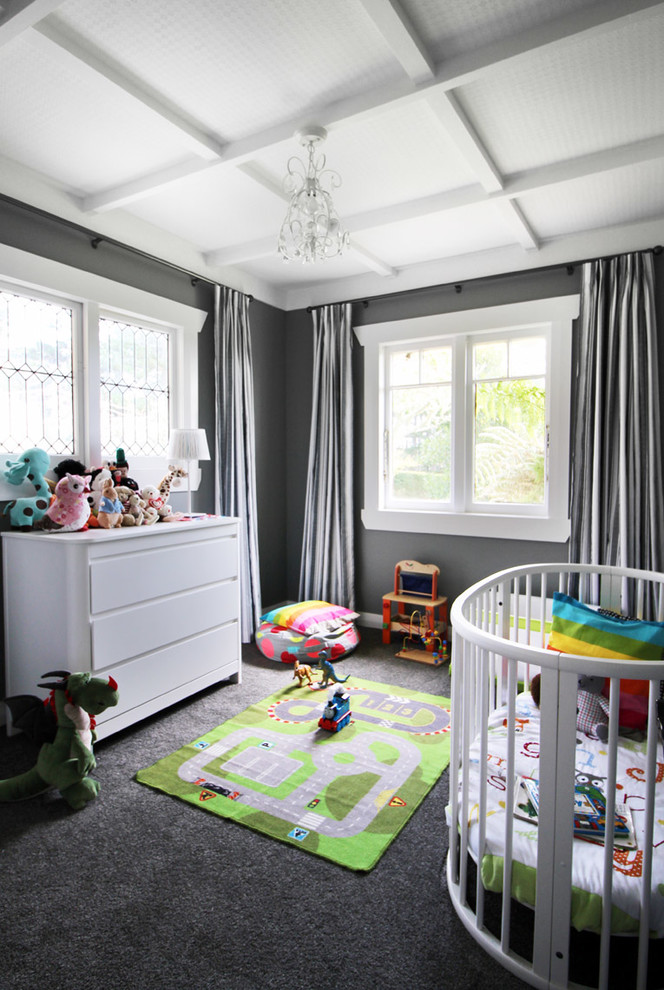 Transitional gender-neutral nursery in Auckland with grey walls, carpet and grey floor.