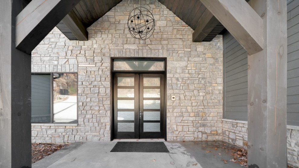 Diseño de puerta principal abovedada clásica grande con paredes grises, suelo de cemento, puerta doble, puerta negra y suelo gris