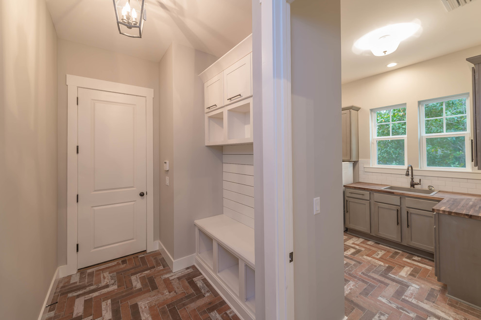 Mid-sized beach style galley utility room in Jacksonville with white cabinets, wood benchtops, grey walls, ceramic floors, a side-by-side washer and dryer, shaker cabinets and a drop-in sink.
