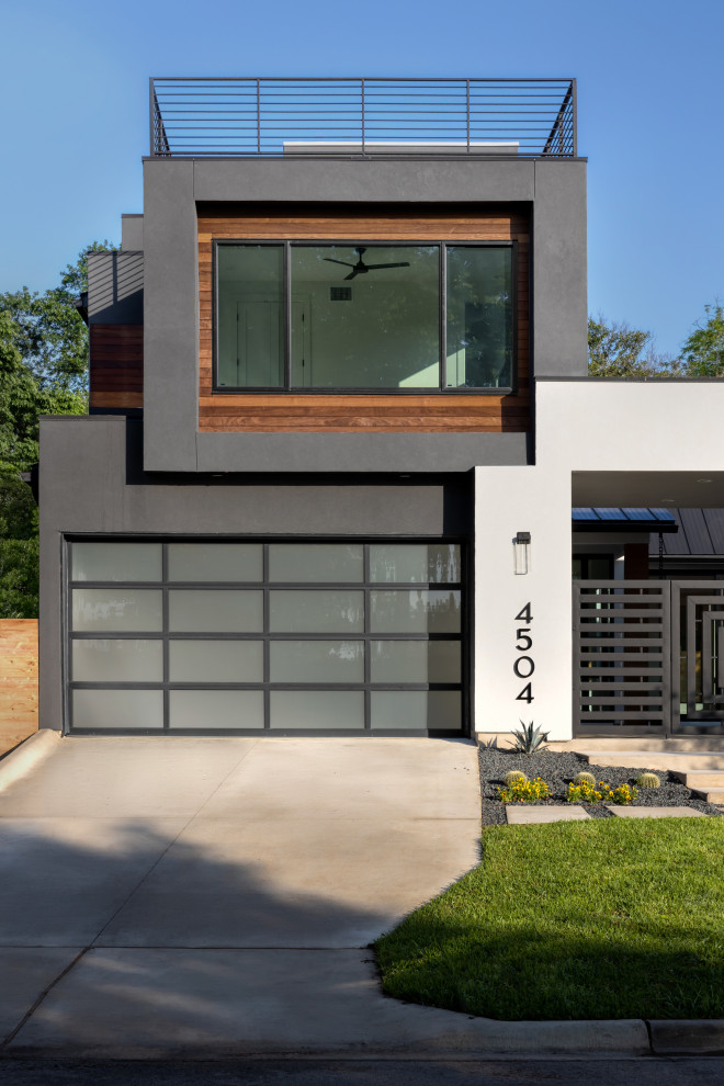Großes, Dreistöckiges Modernes Einfamilienhaus mit Putzfassade, schwarzer Fassadenfarbe, Flachdach, Blechdach und schwarzem Dach in Austin