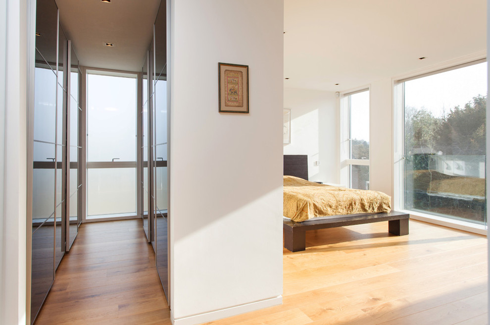 This is an example of a contemporary bedroom in Hampshire with white walls, light hardwood floors and no fireplace.