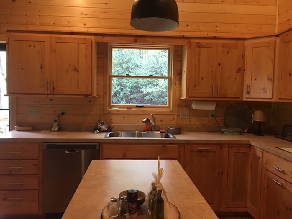 Example of a large mountain style l-shaped medium tone wood floor and brown floor kitchen design with a double-bowl sink, shaker cabinets, light wood cabinets, solid surface countertops, brown backsplash, wood backsplash and stainless steel appliances