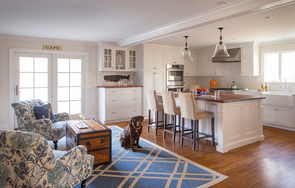 This is an example of a mid-sized beach style open plan kitchen in Boston with a farmhouse sink, shaker cabinets, white cabinets, white splashback, subway tile splashback, medium hardwood floors and with island.