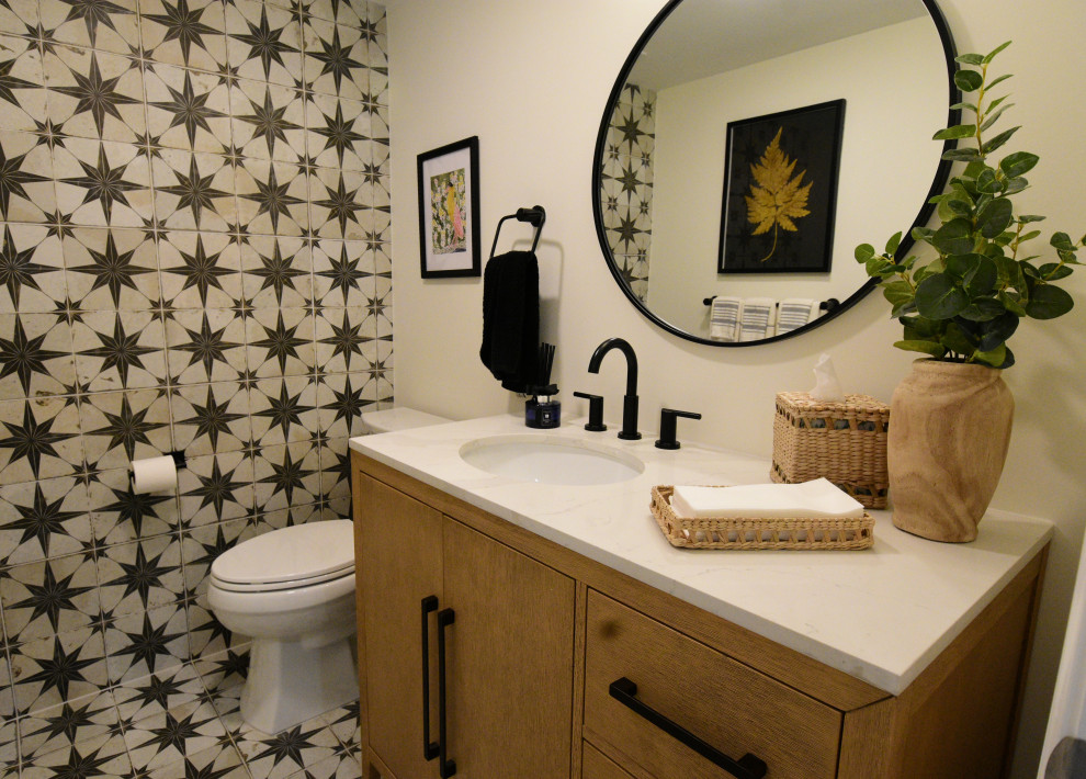 Powder room - small farmhouse black and white tile and ceramic tile ceramic tile and black floor powder room idea in Philadelphia with flat-panel cabinets, light wood cabinets, a two-piece toilet, white walls, an undermount sink, quartz countertops, white countertops and a freestanding vanity