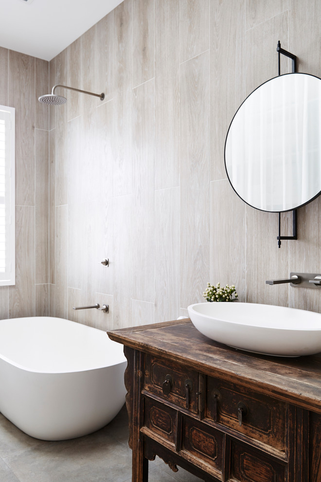 Inspiration for a mid-sized contemporary master bathroom in Sydney with furniture-like cabinets, dark wood cabinets, a freestanding tub, a shower/bathtub combo, a one-piece toilet, gray tile, porcelain tile, grey walls, porcelain floors, a vessel sink, grey floor and an open shower.