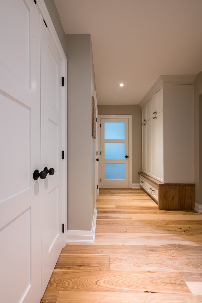 Photo of a mid-sized contemporary foyer with grey walls, light hardwood floors and beige floor.