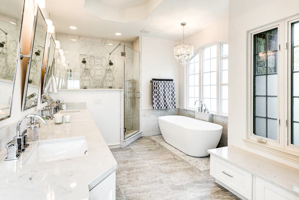 Photo of a large transitional bathroom in Dallas with white cabinets, a hot tub, a corner shower, marble, white walls, porcelain floors, a drop-in sink, quartzite benchtops, grey floor and a hinged shower door.